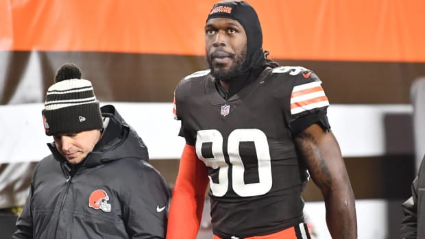 Browns pass rusher Jadeveon Clowney walks off the field with a trainer during a game.